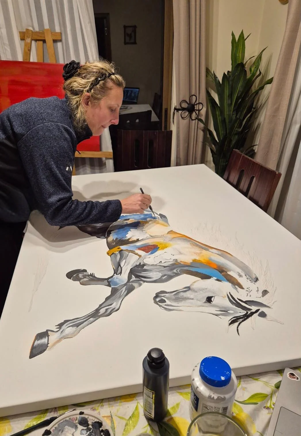 Catherine trabajando en una pintura de caballo con pincel y pinturas