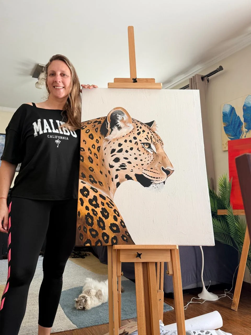 Catherine Eberlein junto a su pintura de un leopardo, en su espacio de creación